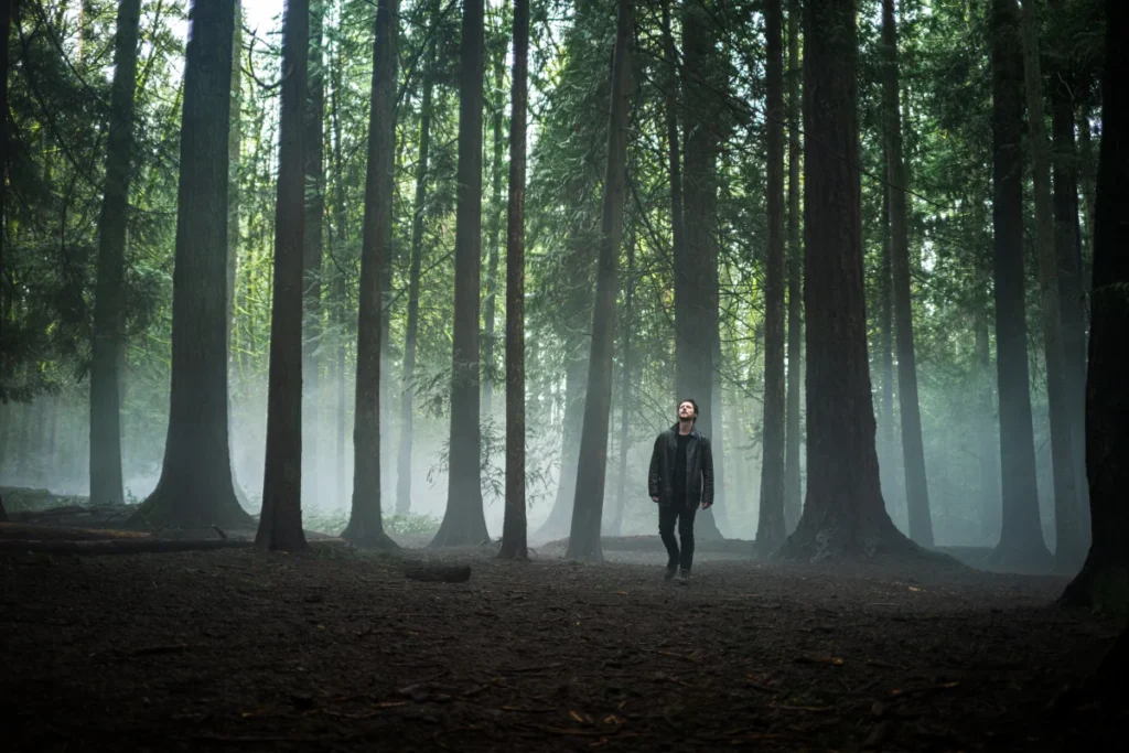 Noah Reid as a private investigator walking through a misty forest in the Crave series Yaga